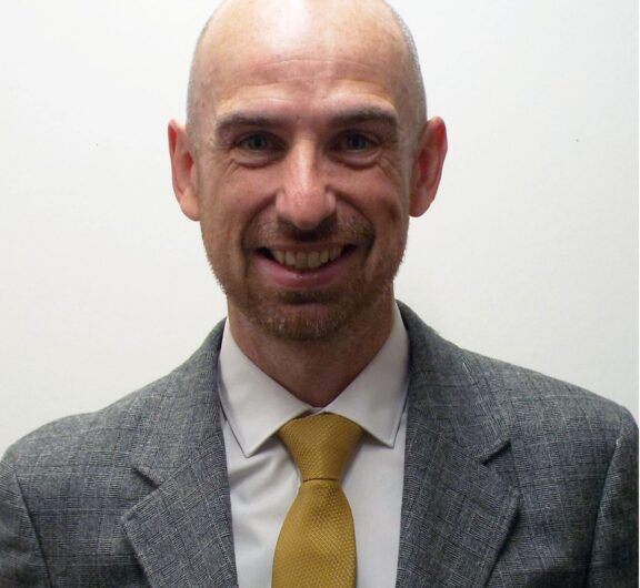 Portrait of a smiling man in a suit Kevi Foundation