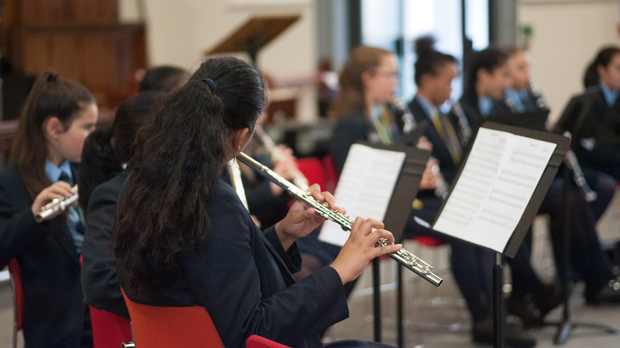 Students playing musical instruments in school uniform, a girl playing the flute.