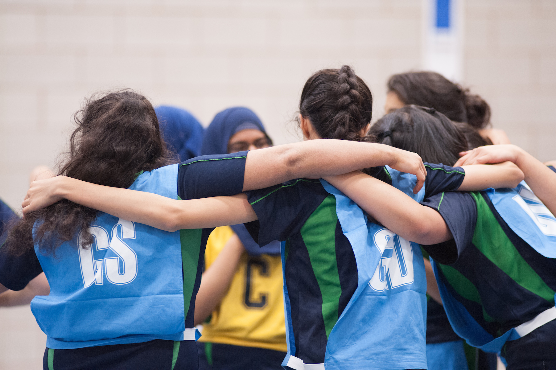 Girls in sports jerseys with arms around each other.