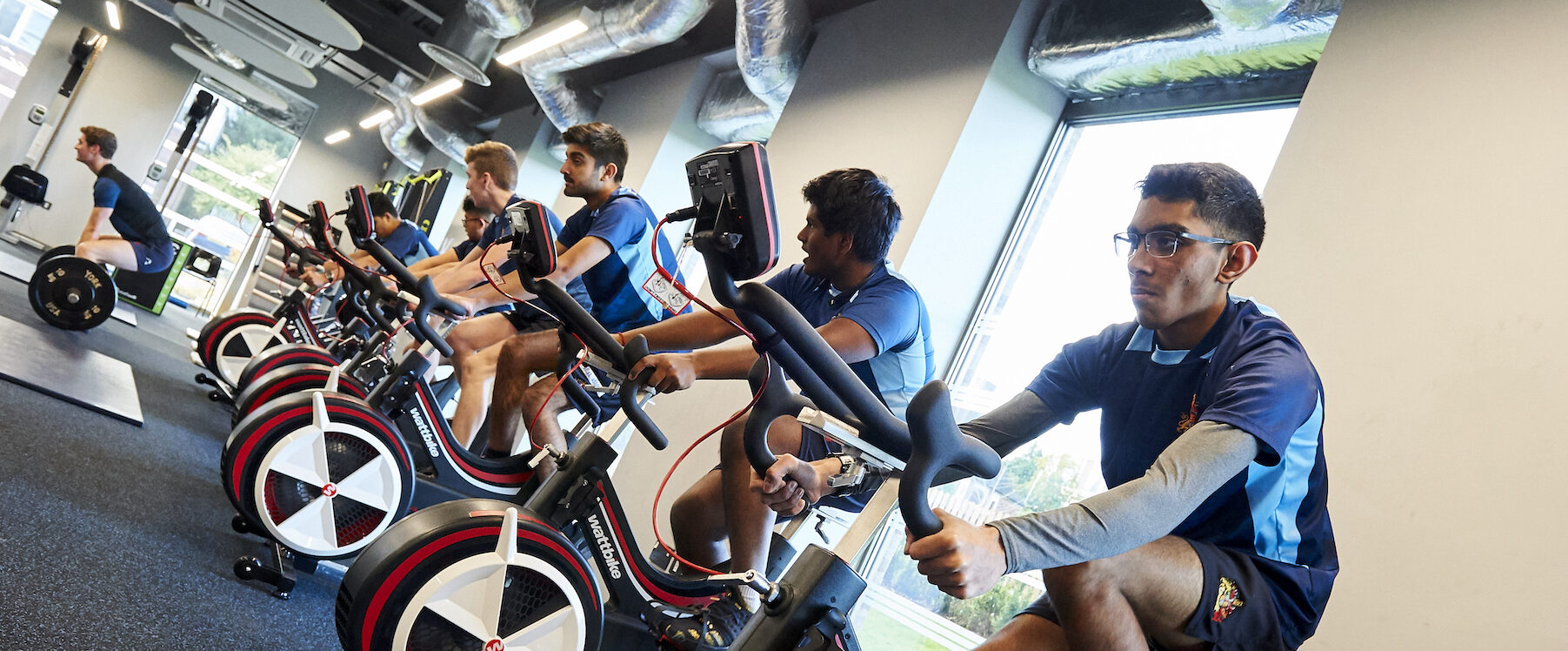 Students engaging in a spin class on exercise bikes in a fitness class.