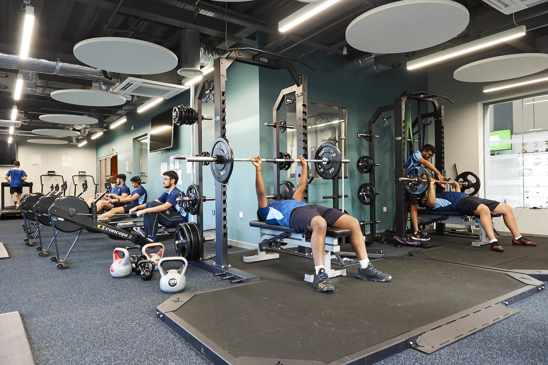 Students engage in various exercises in a modern gym, promoting fitness and well-being in a safe environment.