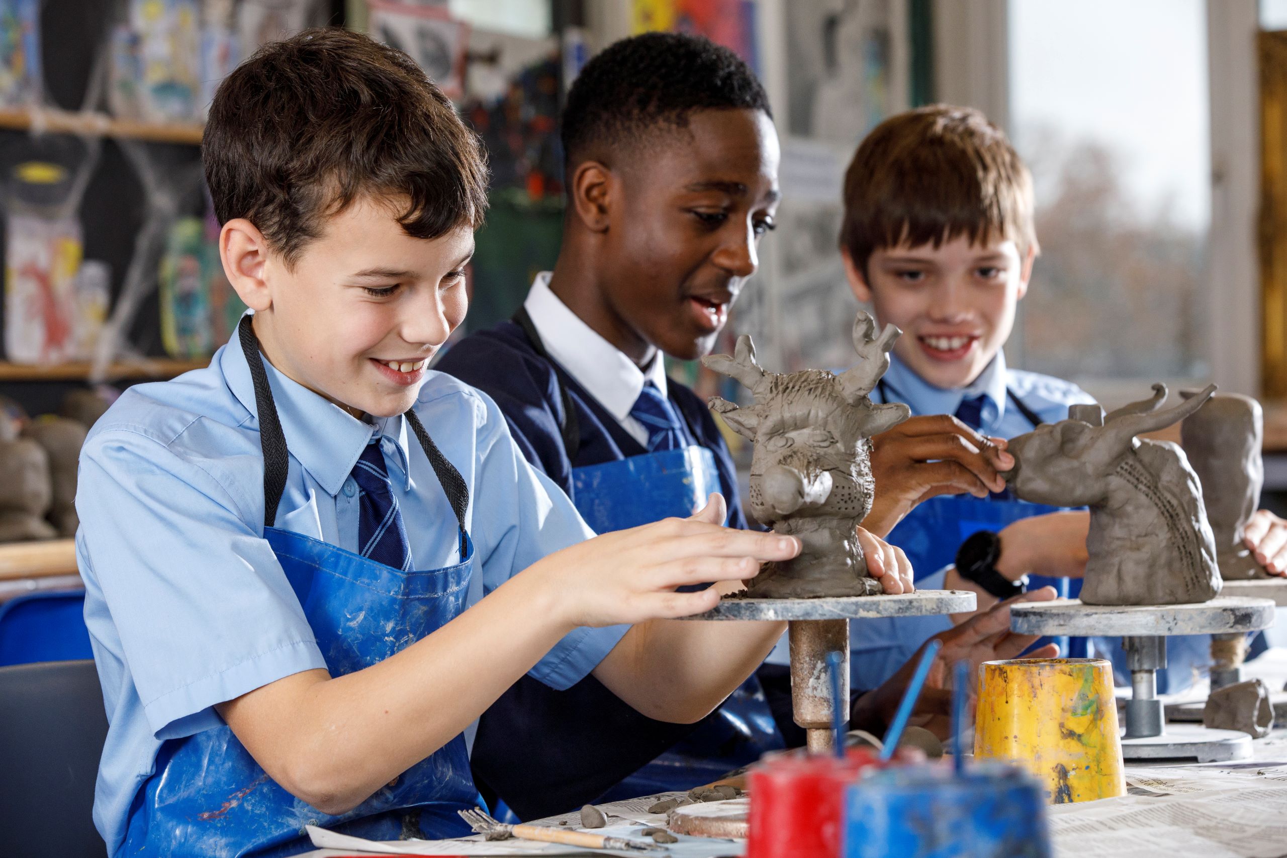 Students in uniform engaged in art class, working with clay sculptures.