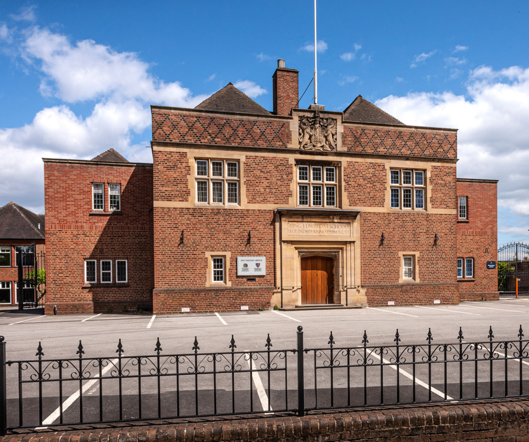 Main entrance of the Kevi Foundation campus, featuring a historic red brick building and a flagpole.
