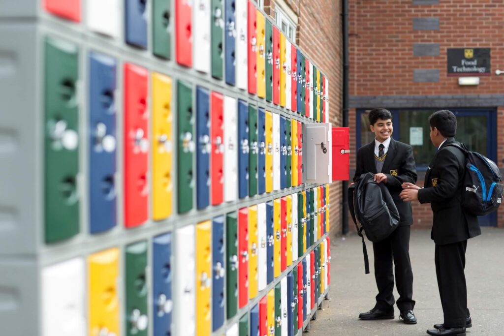 Students in uniform standing near colourful lockers on a secure school campus at Kevi Foundation.