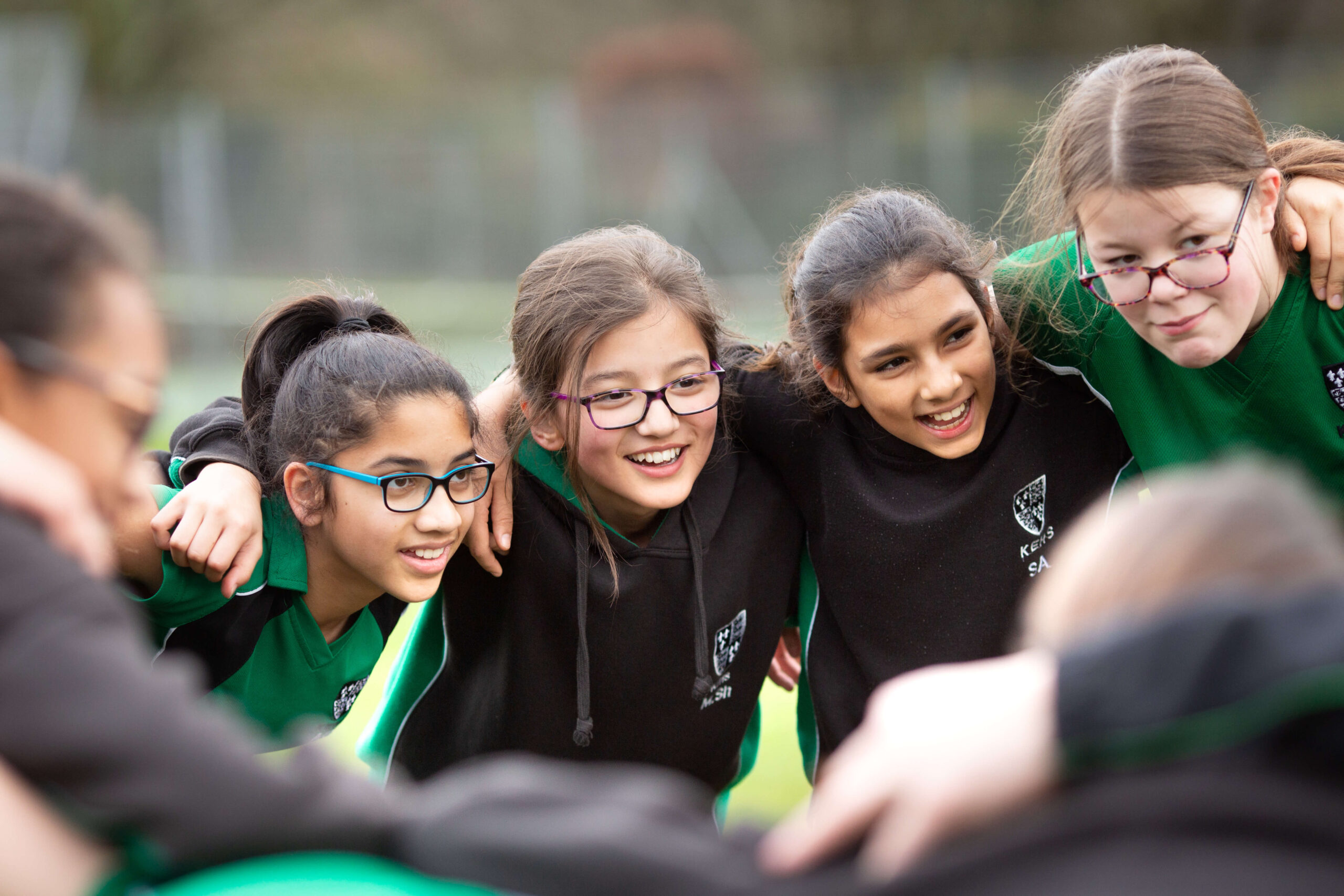 Kevi Foundation students in black and green uniforms smiling in a group, participating in teamwork activities.