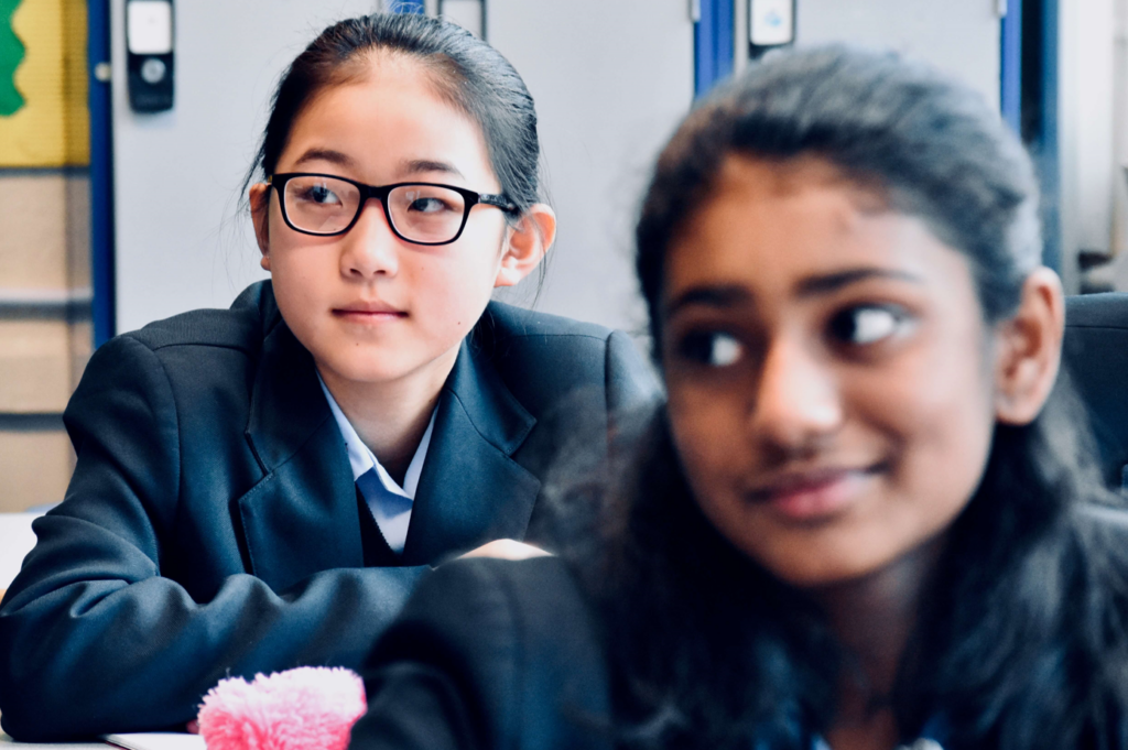 Two students in school uniforms engaged in a group activity, focusing on collaborative learning and academic engagement at Kei Foundation.
